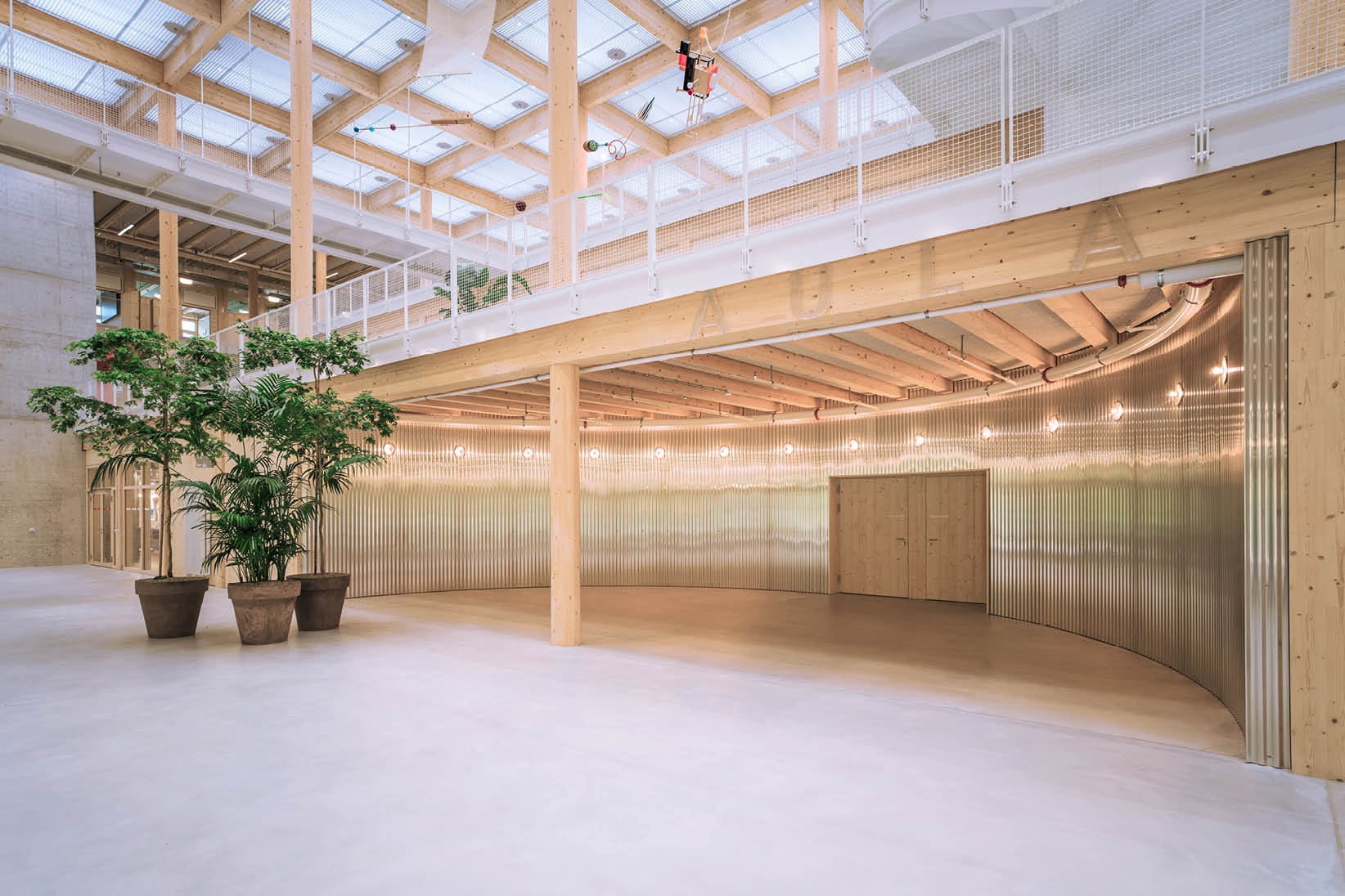 Moderner Innenraum mit Holzst tzen, einer Galerie mit Gel nder, gro en Pflanzen in T pfen und einer wellenf rmigen Metallwand im Hintergrund. Beschreibung von KI generiert